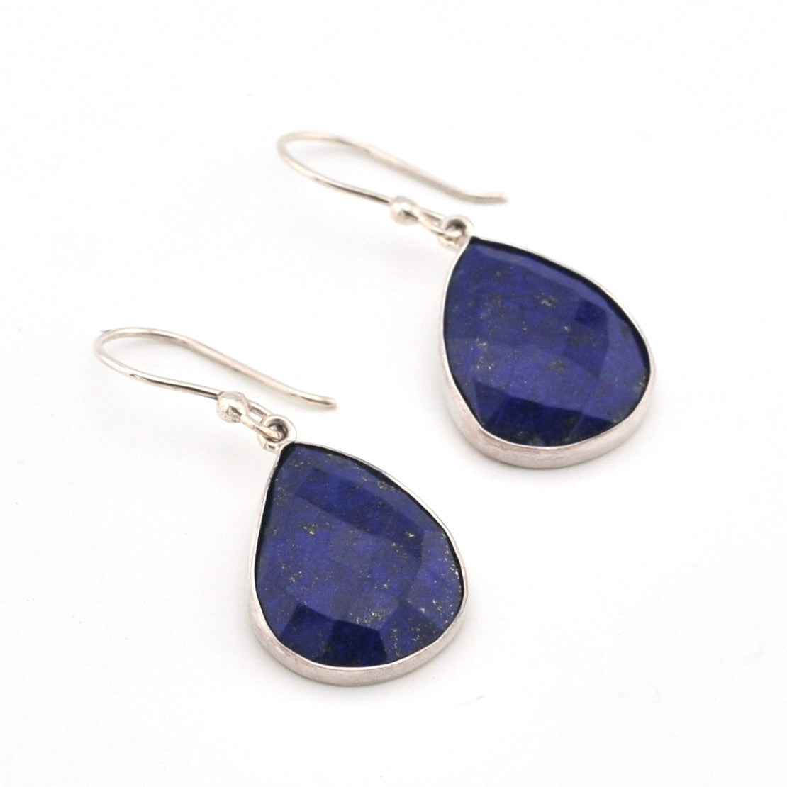 Teardrop-shaped lapis lazuli earrings with silver hooks on a white background