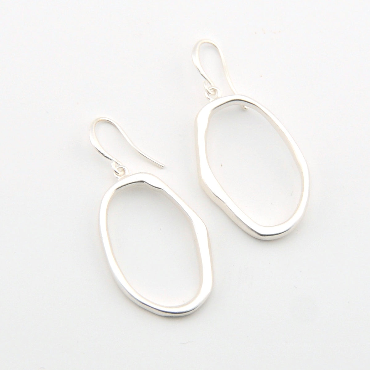 Silver oval earrings on a light gray background