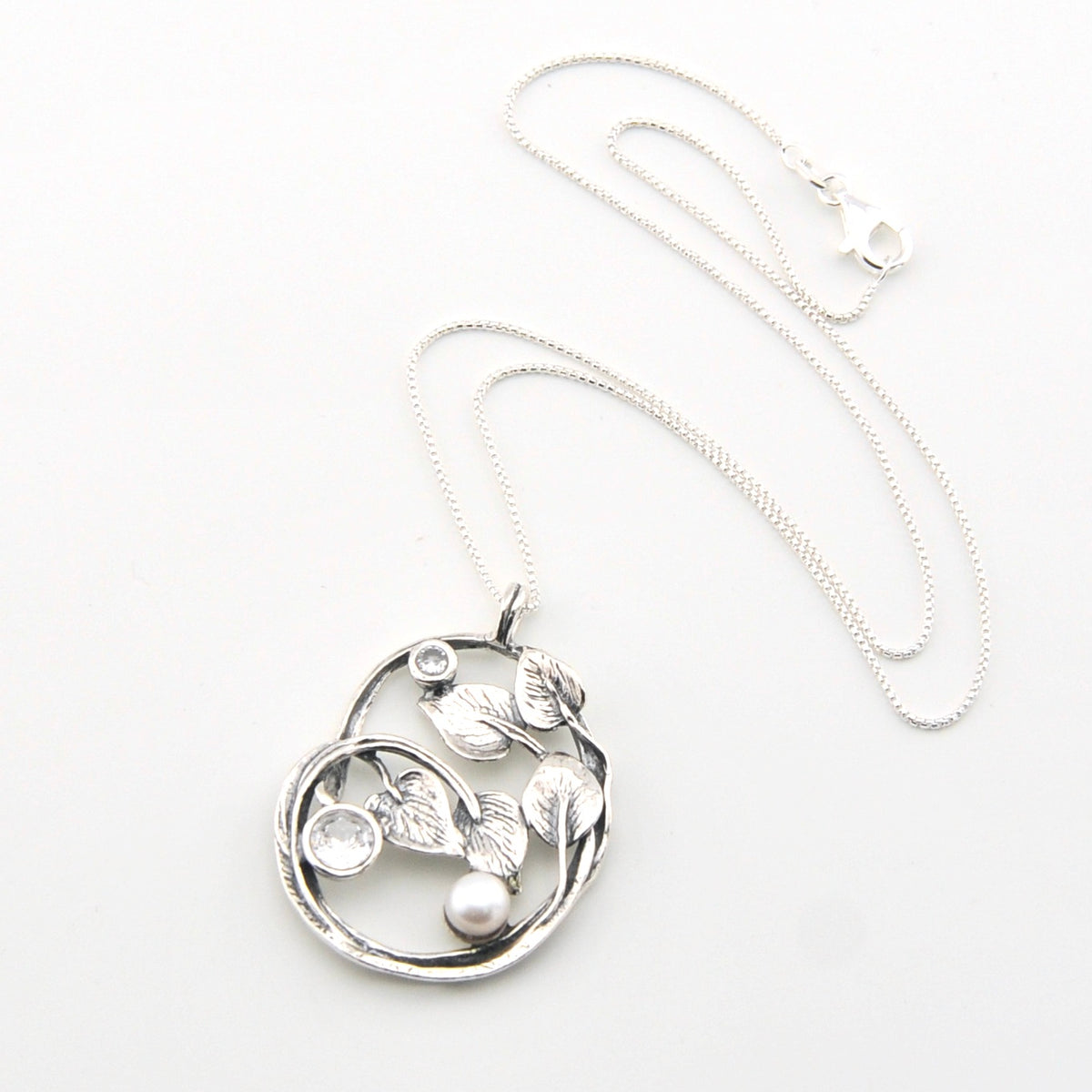 Silver necklace with a leaf-shaped pendant on a white background