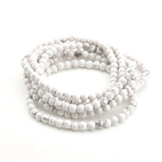 Stack of white beaded bracelets on a white background