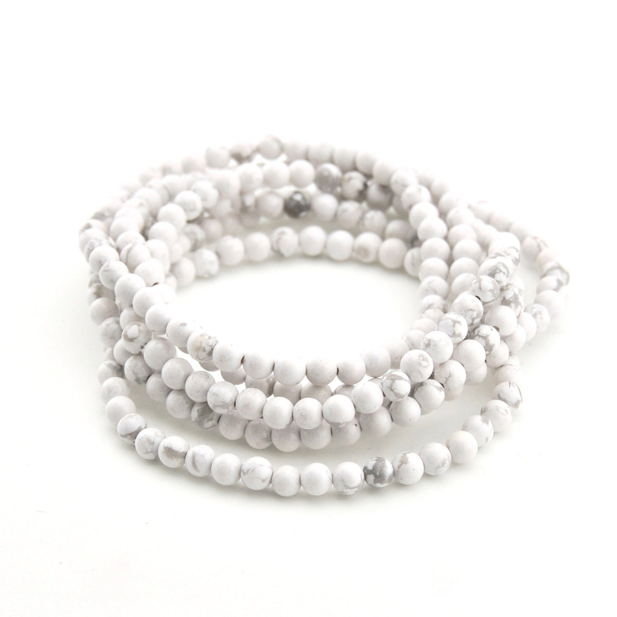 Stack of white beaded bracelets on a white background