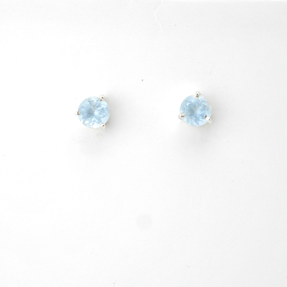 Pair of round light blue gemstone stud earrings on a white background