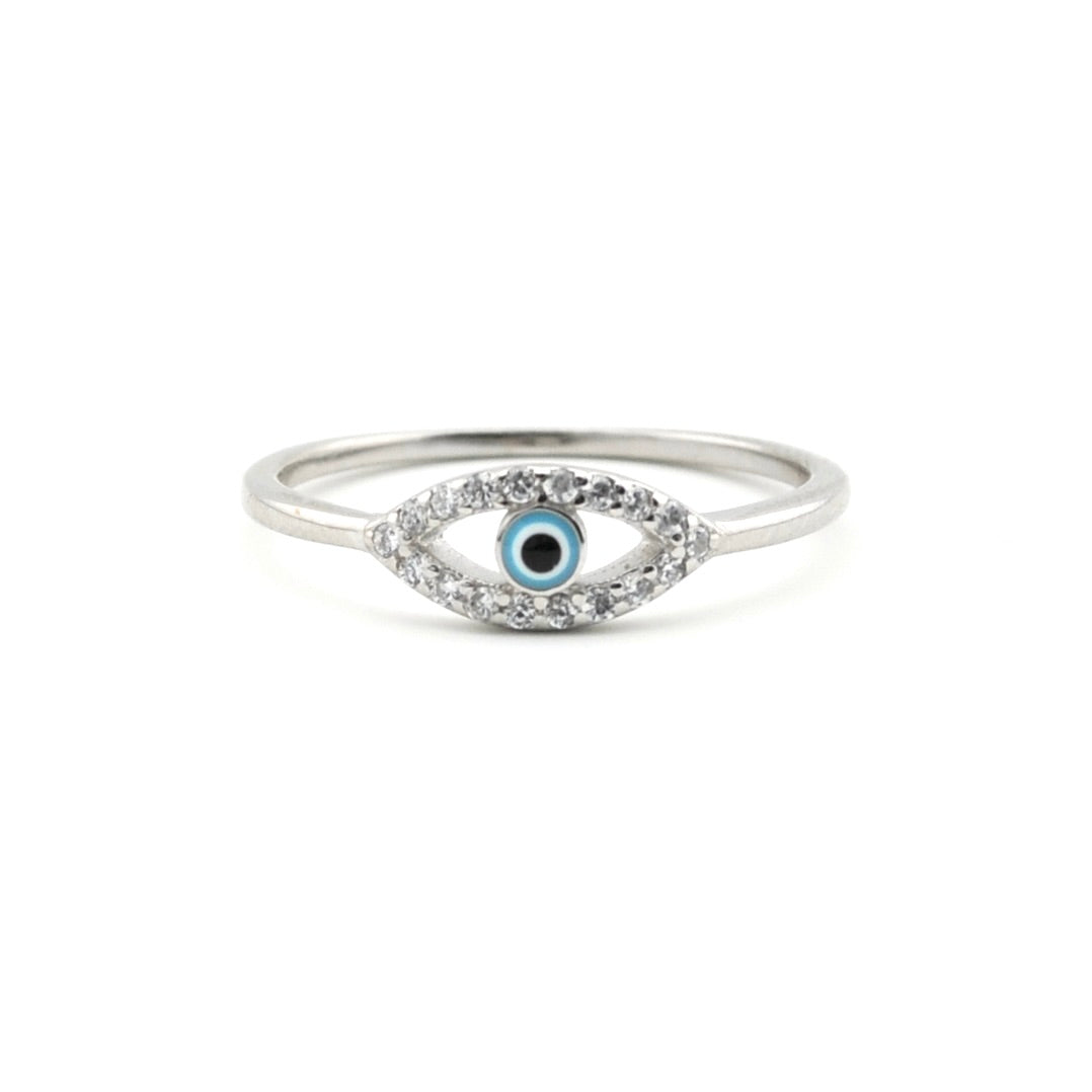 A silver-toned evil eye ring featuring a central blue and black eye motif surrounded by small clear stones, set against a plain white background.