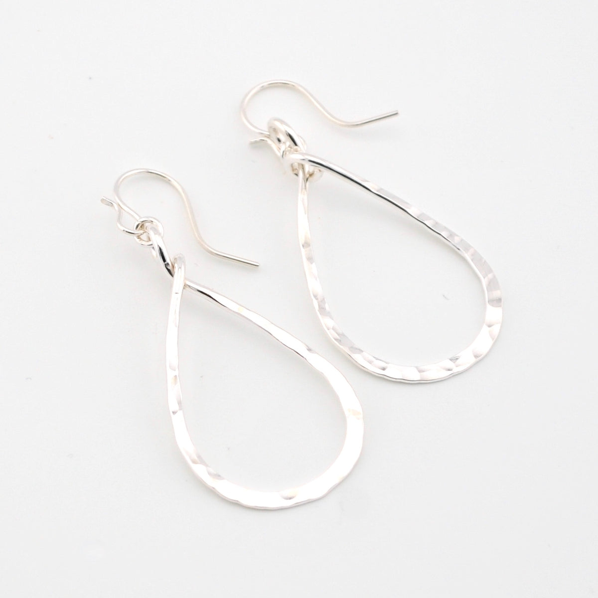 Silver teardrop earrings on a light gray background