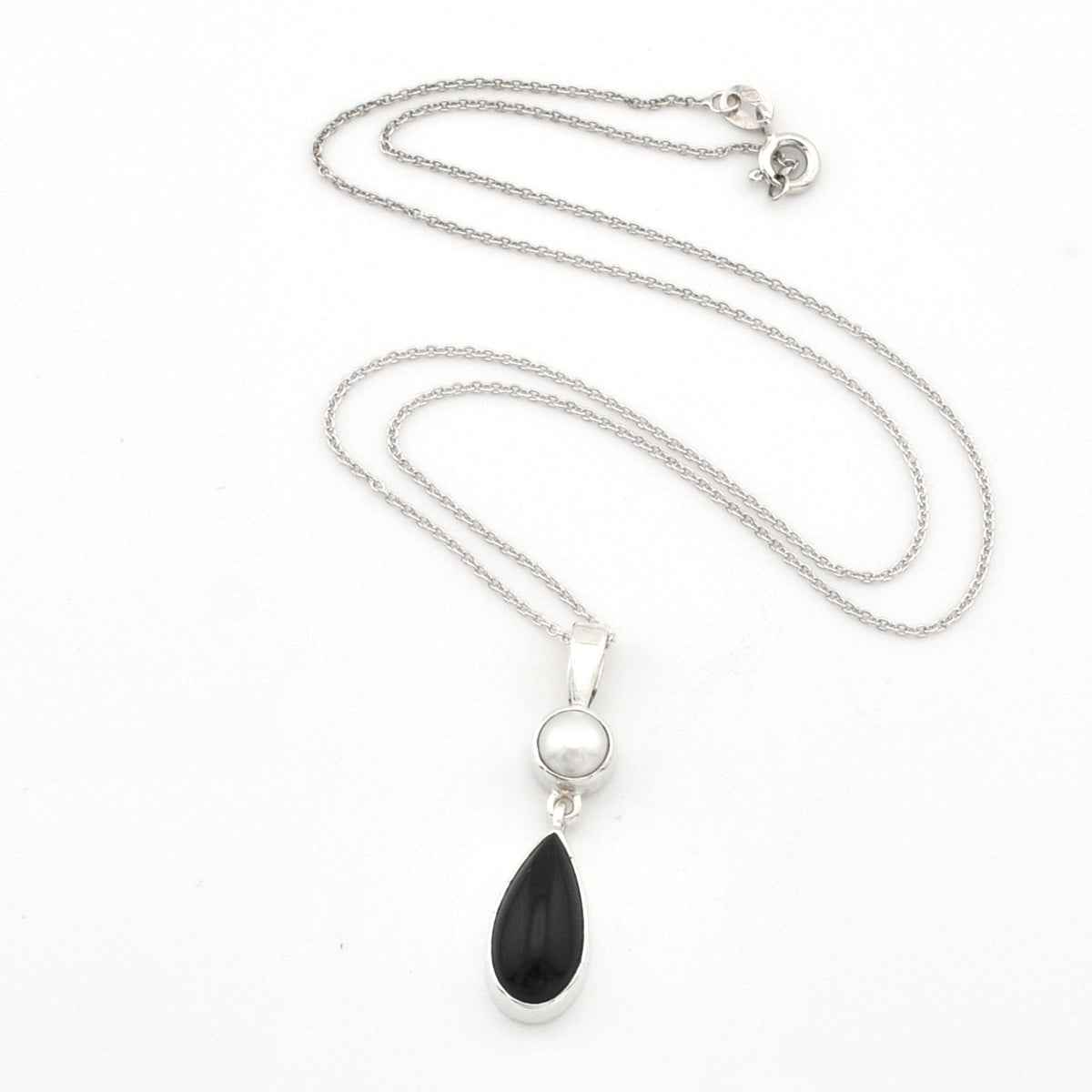 A silver necklace featuring a teardrop-shaped black onyx pendant and a small round white pearl, displayed on a clean white background.