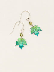 A pair of dangling earrings featuring green and blue iridescent maple leaf charms suspended from silver fishhook wires with small green faceted beads, set against a plain off-white background.