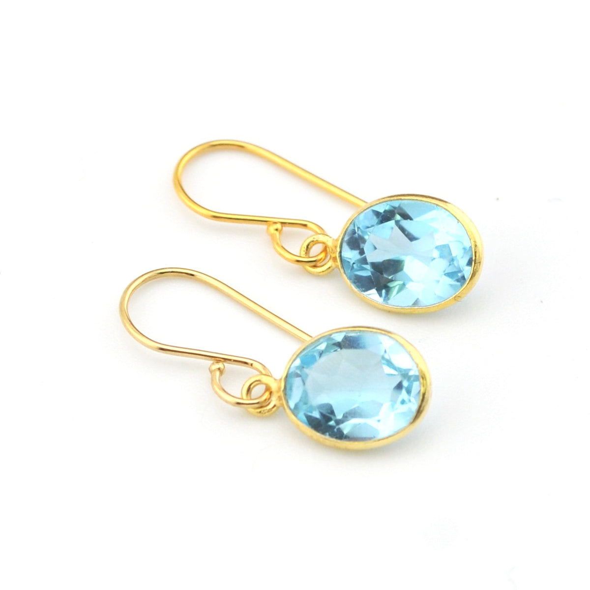 Gold earrings with blue gemstones on a white background