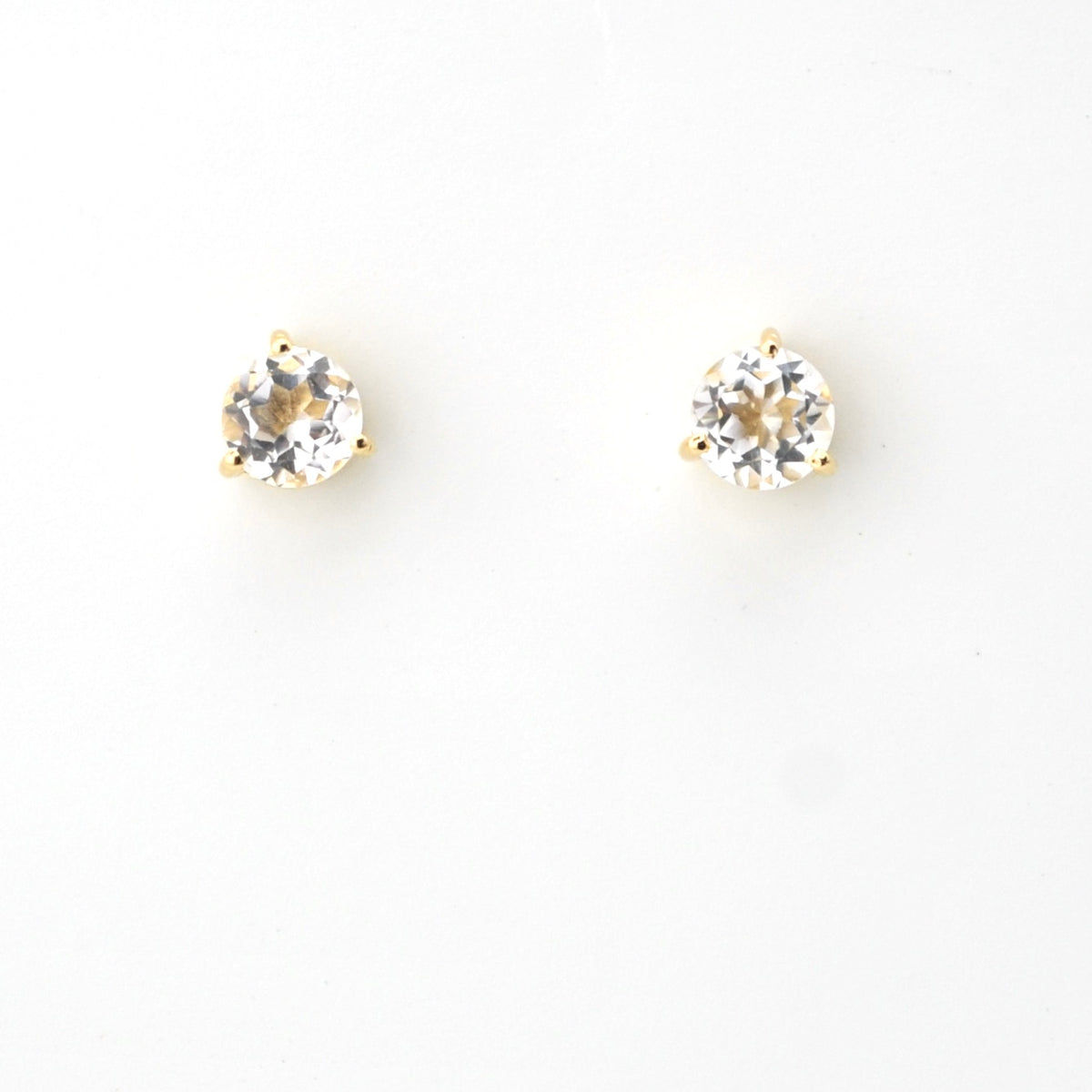 Pair of gold stud earrings with clear gemstones on a white background